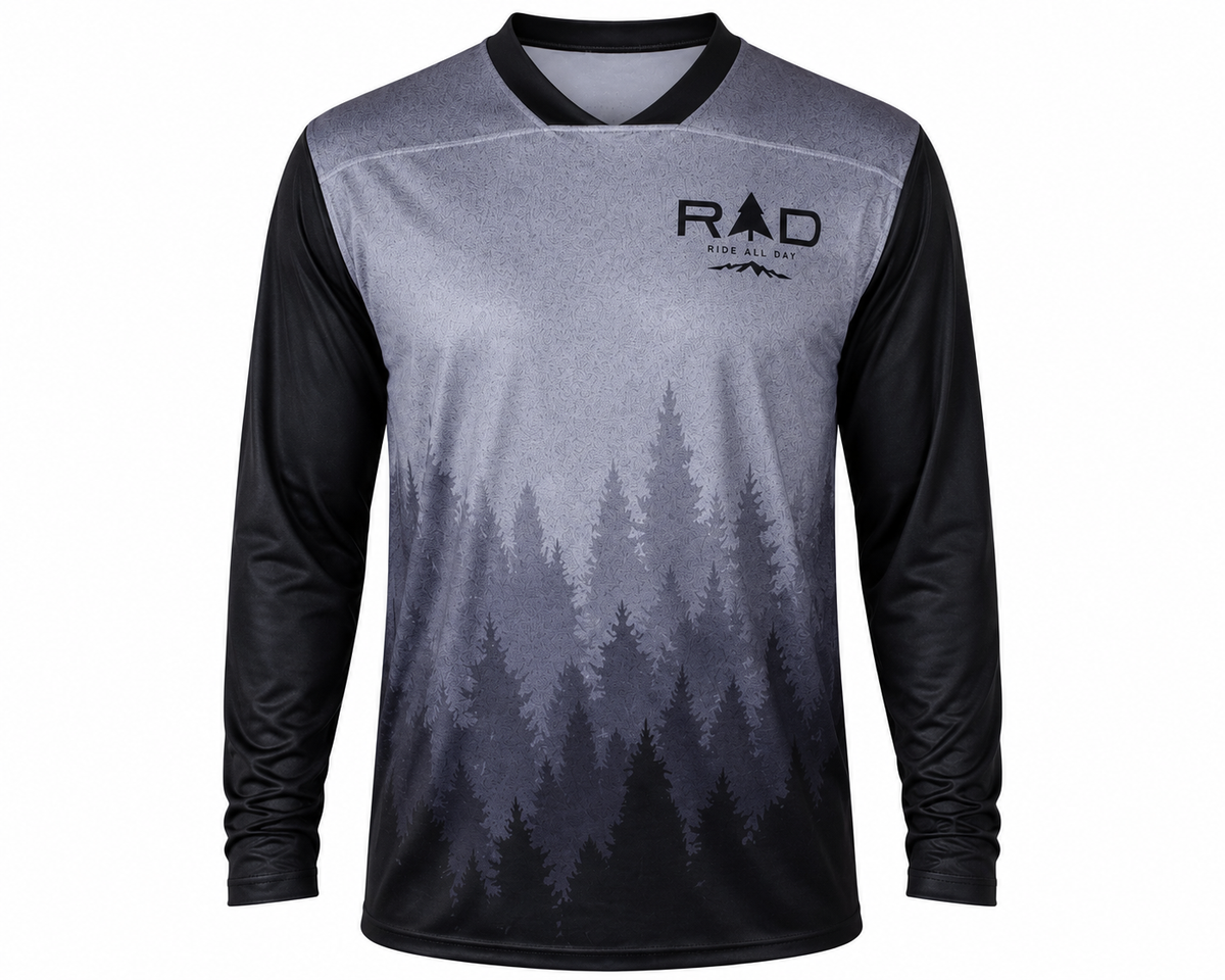 A long-sleeve cycling jersey with a gray and black forest tree gradient print, featuring a black collar and the 'Ride All Day' logo on the left chest, displayed on a solid gray background.